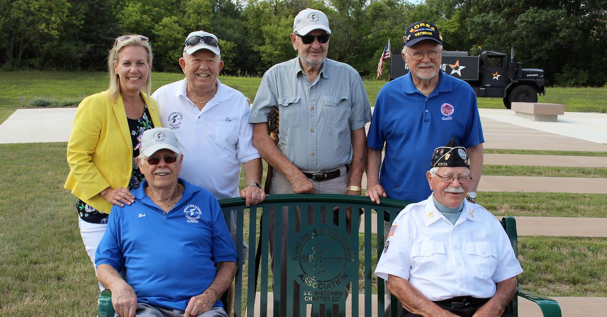 County Executive Kerkman and Korean War Veterans posing on commemorative bench